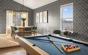 A pool table with a cue stick and balls, a dining area with chairs and a table, and a window with a view. - 2 Homes 7BR Sleeps 18 Pool Amazing Mtn Views (Tucson)