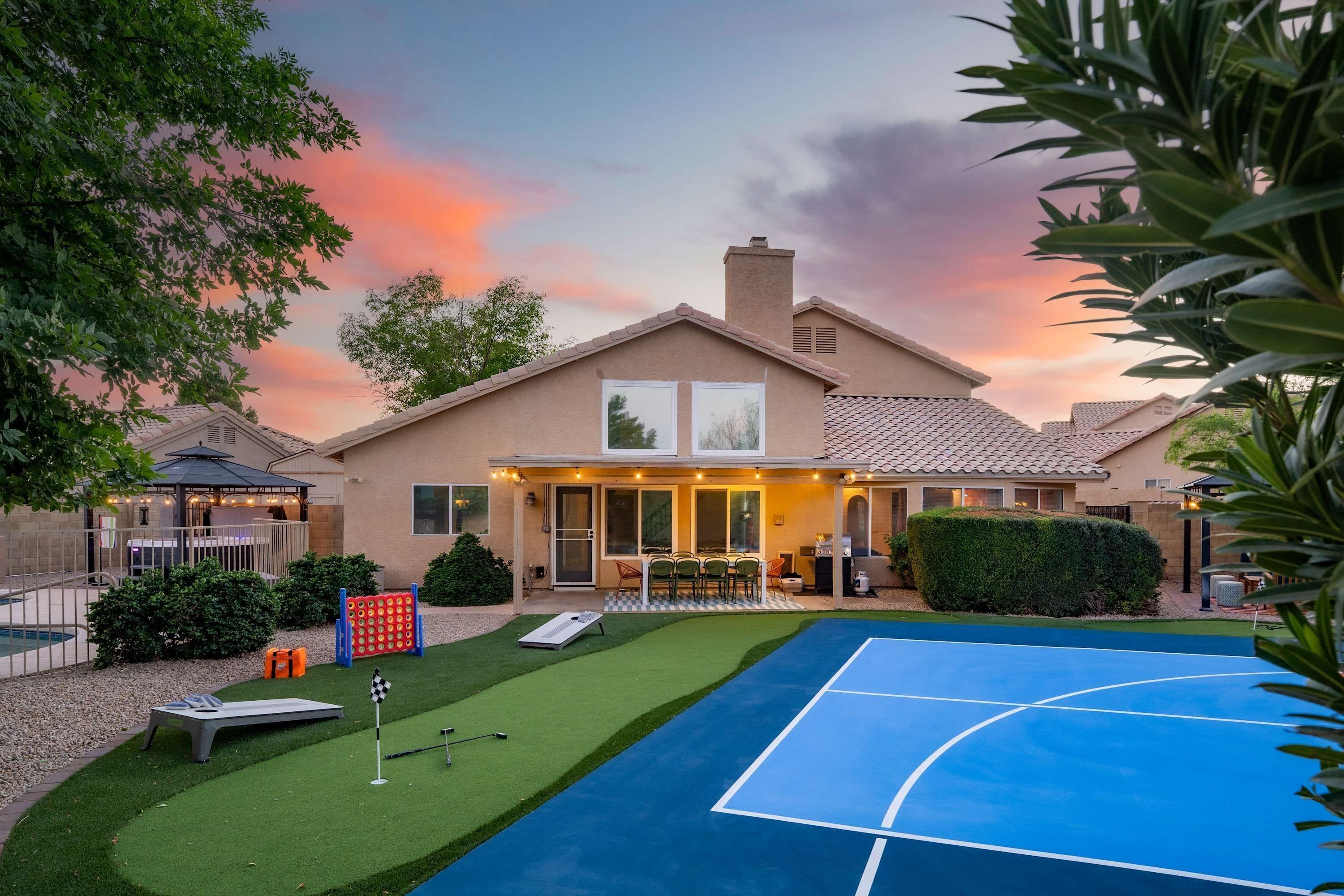 A residential property with a tennis court, a covered patio, and a swimming pool.