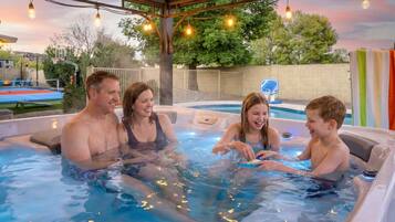 A hot tub with four people, surrounded by a covered area with string lights.