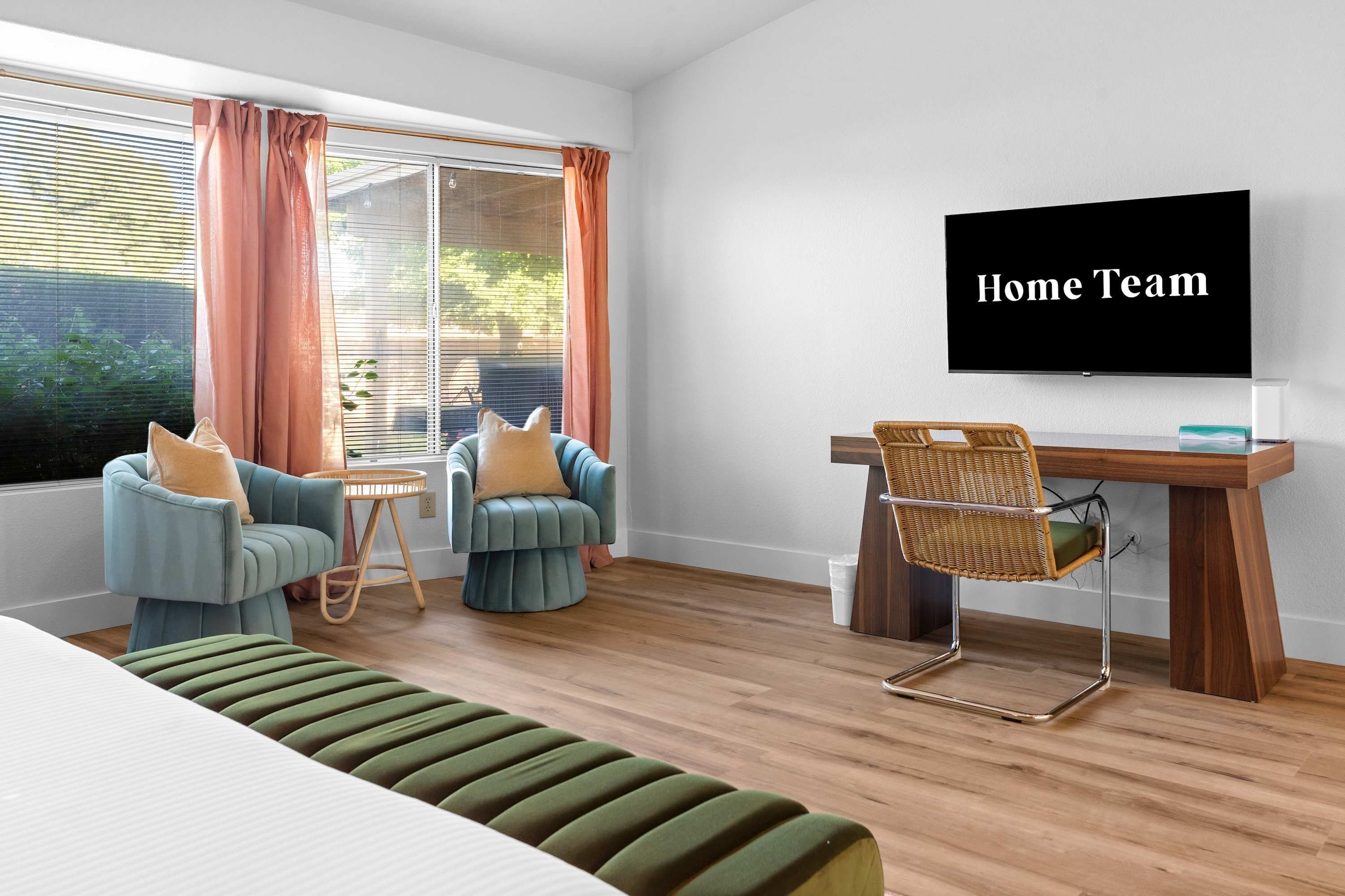 A modern living room with a sofa, two armchairs, a coffee table, a dining table with chairs, and a television on the wall.
