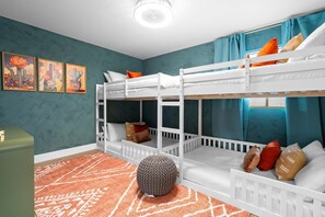 A bunk bed room with a teal wall, a patterned rug, and a green chest of drawers. - Desert Oasis Pool Spa Pickleball Theater (Glendale)