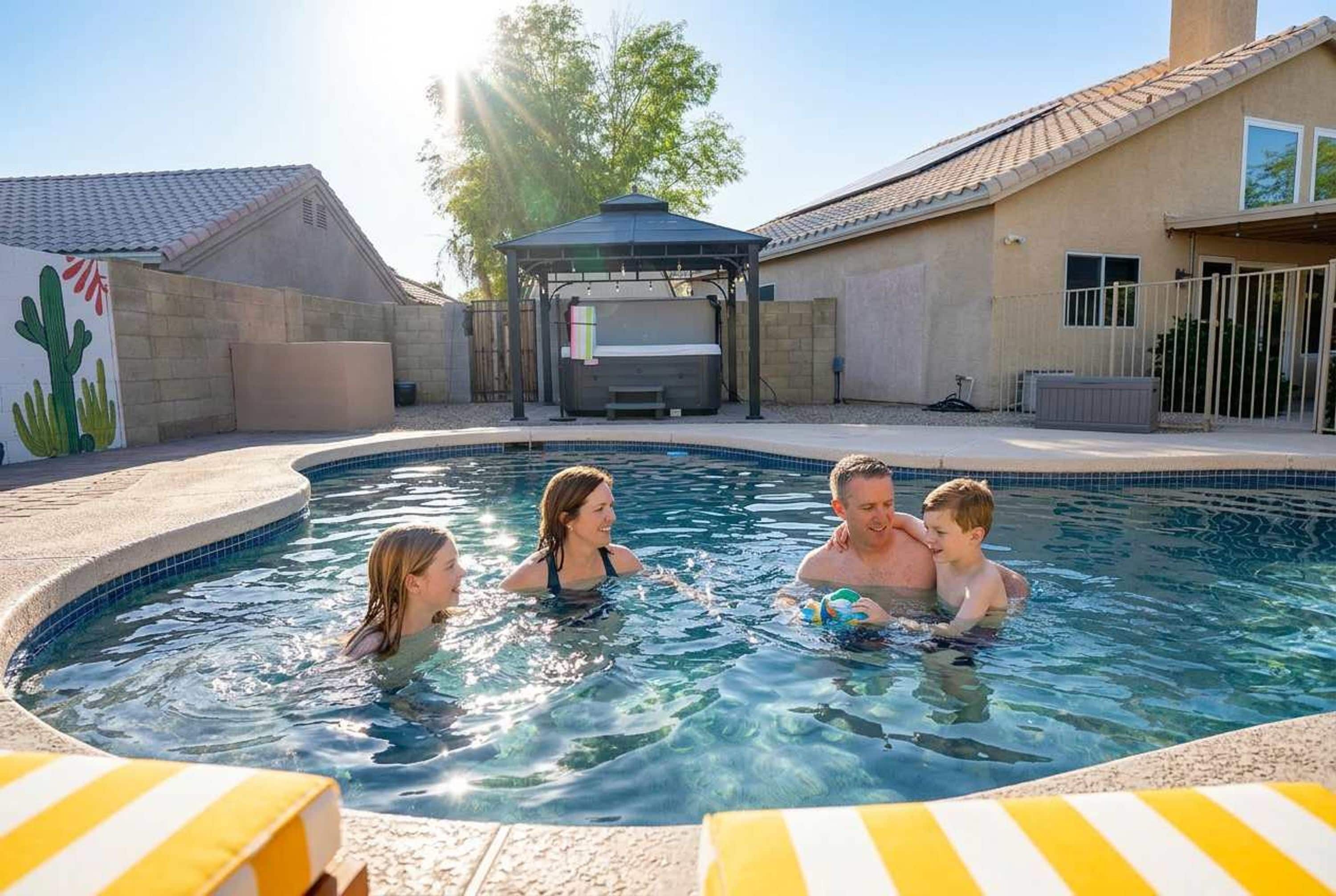 A swimming pool with a hot tub and a covered seating area.
