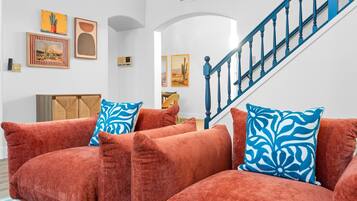 A living room with a sofa set, a staircase, and wall art.