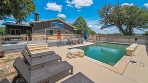 A residential property with a swimming pool, outdoor seating, and a large house. - The Juniper Pickleball Private Pool (Fredericksburg)