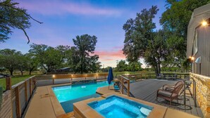 A swimming pool with a deck, surrounded by trees and a sunset sky. - The Juniper Pickleball Private Pool (Fredericksburg)
