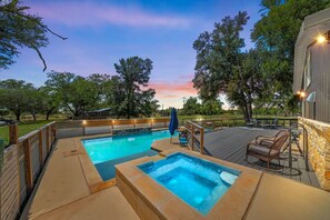 Ein Schwimmbecken mit Sonnendeck, umgeben von Bäumen und einem Abendhimmel.