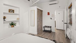 A bedroom with a bed, a shelf with decorative items, a wardrobe, and a radiator. - Private Pool Patio Games BBQ Family Fun (Fort Lauderdale)