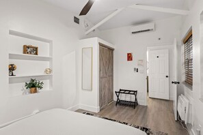 Ein Schlafzimmer mit einem Bett, einem Regal mit Dekoration, einem Kleiderschrank und einer Heizung.