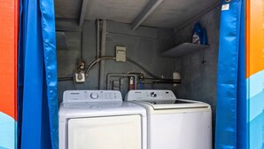 A laundry room with two white washing machines, a blue detergent bottle, and a water heater. - Private Pool Patio Games BBQ Family Fun (Fort Lauderdale)