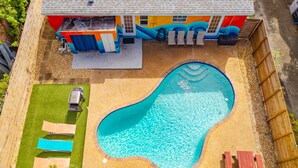 A swimming pool with a curved edge, surrounded by a fenced yard with a patio area and lounge chairs. - Private Pool Patio Games BBQ Family Fun (Fort Lauderdale)