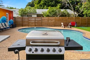 A backyard with a swimming pool, a barbecue grill, and a wooden fence. - Private Pool Patio Games BBQ Family Fun (Fort Lauderdale)