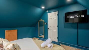 A bedroom with a bed, a TV, a door, and a mirror.