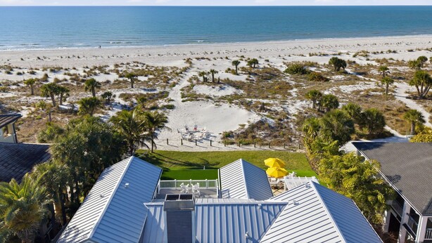 Blick auf einen Strand von einem Hotel mit Poolbereich und Liegestühlen.