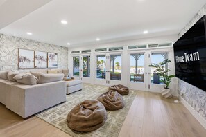 A modern living room with a sofa, bean bags, and a large TV screen. - Award-winning Private Beach Breathtaking Sunsets (Clearwater Beach)