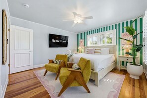 A bedroom with a bed, two chairs, a TV, and a ceiling fan. - Award-winning Private Beach Breathtaking Sunsets (Clearwater Beach)