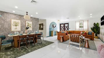 A spacious living area with a dining table set for four, a sofa, and a coffee table.