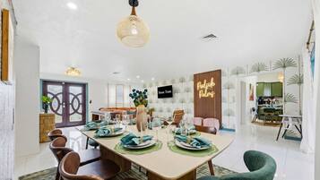 A dining area with a long table set for six, surrounded by wooden chairs.