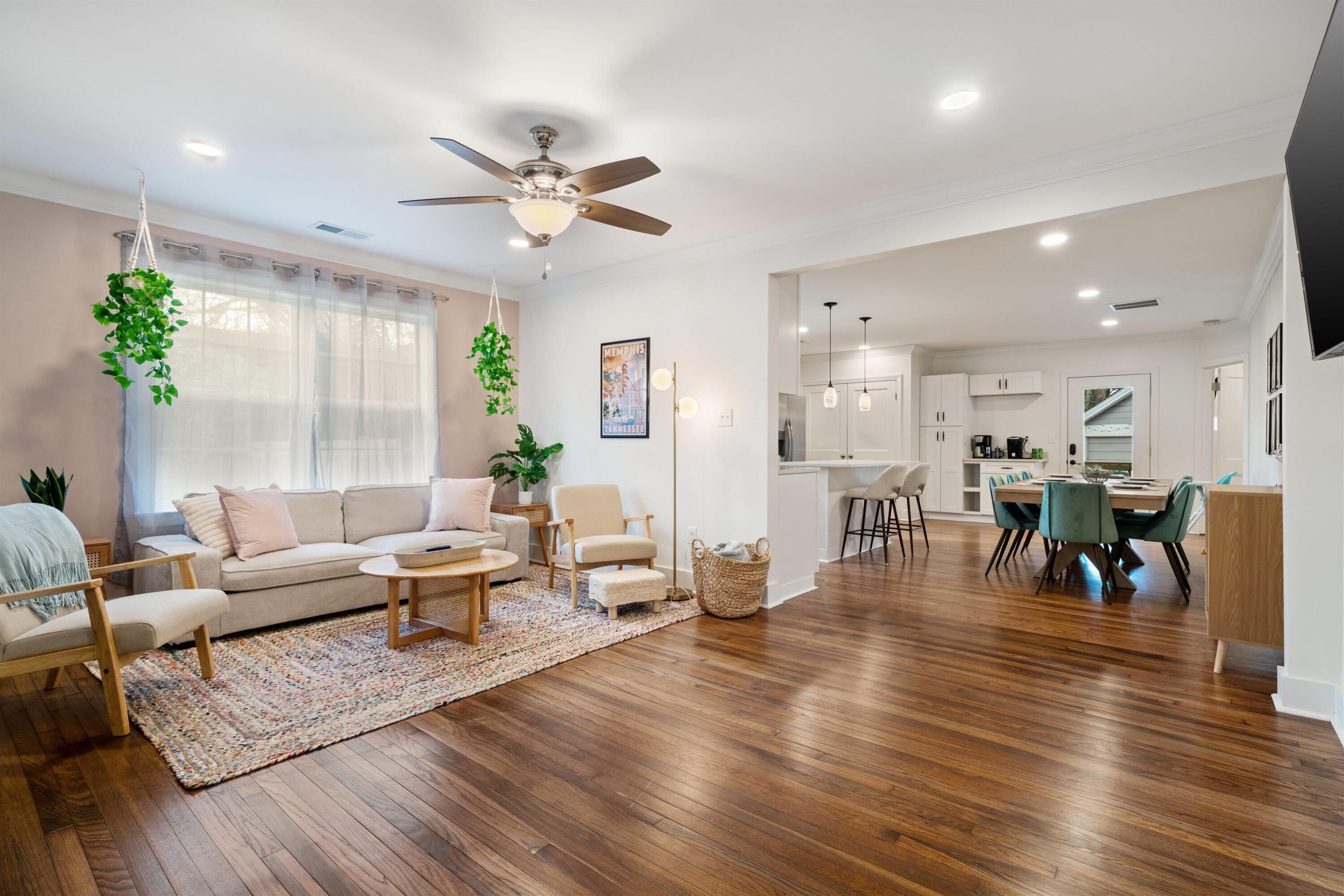 A spacious living room with a sofa, coffee table, and hanging plants.