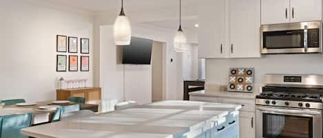 A modern kitchen with white cabinetry, stainless steel appliances, and a central island with blue drawers.