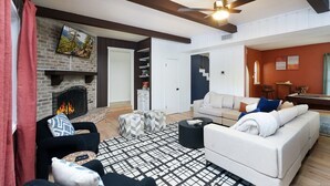 Ein Wohnzimmer mit Kamin, Deckenventilator, Sofa und Fernseher.