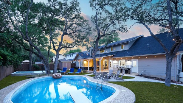 Ein Wohnhausgarten mit Swimmingpool, Gartenmöbeln und einer überdachten Terrasse.