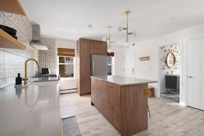 Uma cozinha moderna com ilha central, armários de madeira, geladeira de aço inoxidável e backsplash estampado.
