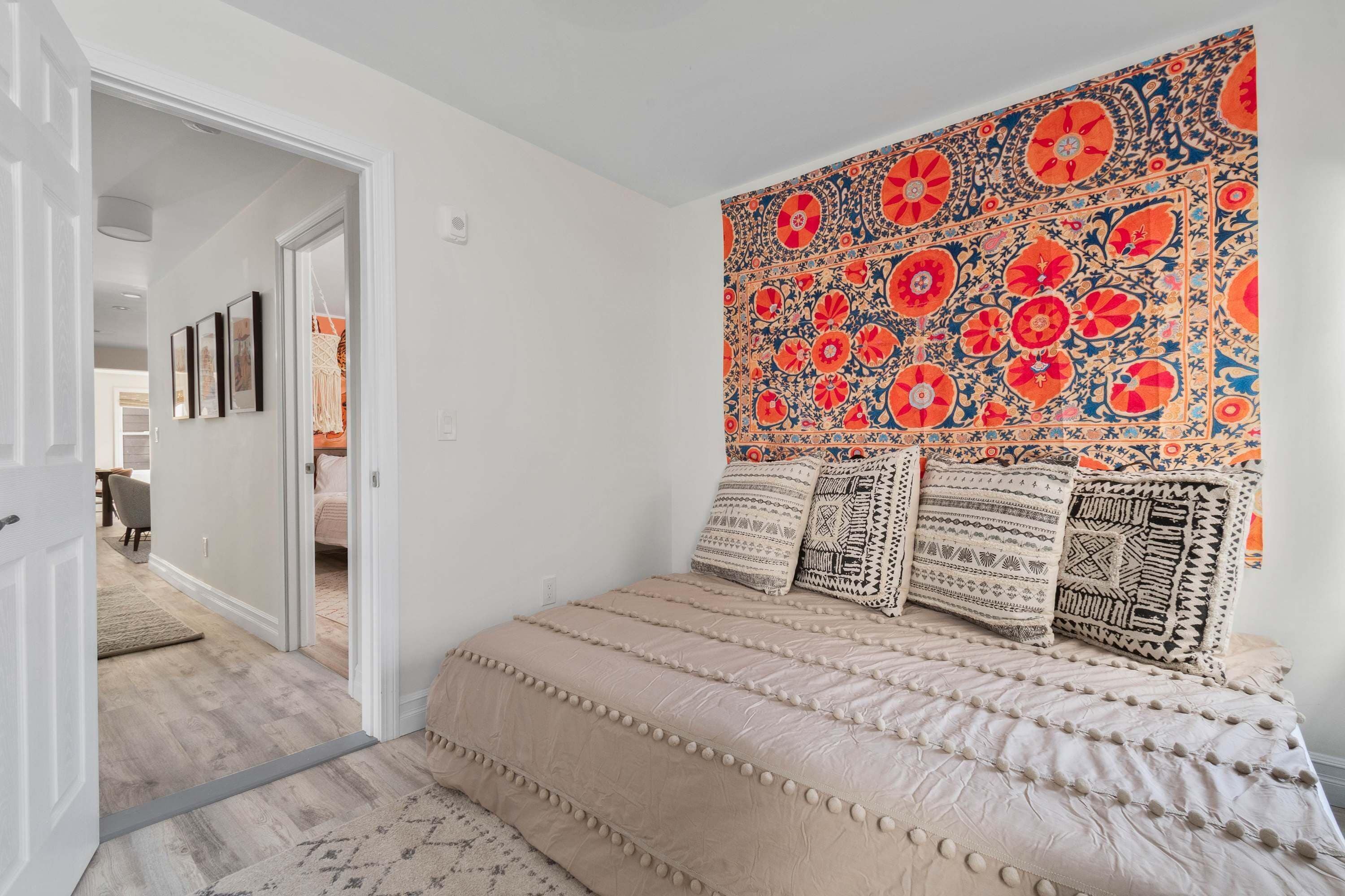 Een slaapkamer met een bed, een wandtapijt en een deur naar een andere kamer.