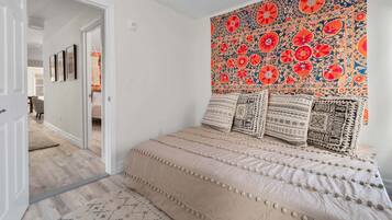 Een slaapkamer met een bed, een wandtapijt en een deur naar een andere kamer.