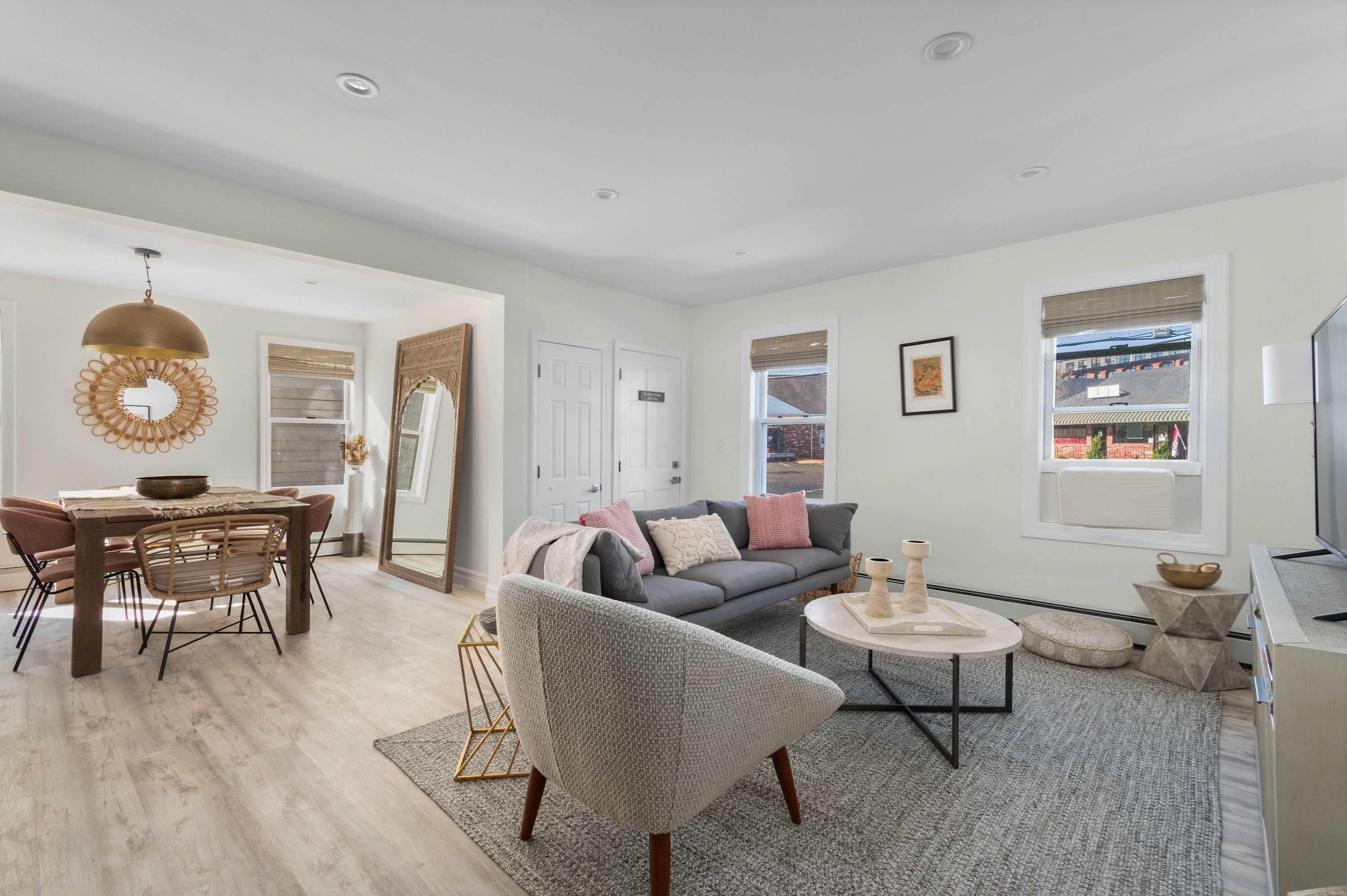 A modern living room with a dining area, a gray sofa, and a round coffee table.