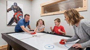 A family playing foosball at a table with a wooden table and a white playing surface. - Mountain View Hot Tub Sauna Fire Pit (Blue Ridge)
