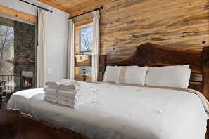 Quarto com cabeceira de madeira, lareira e janela com cortinas.