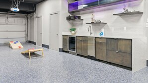 A kitchen area with a sink, cabinets, and a small plant. - Bradenton Beachfront Pool Game Room (Bradenton)
