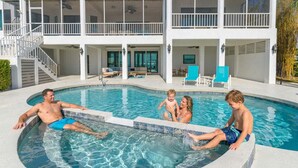 A residential pool area with a two-story house, a covered deck, and a staircase leading to the upper level. - Bradenton Beachfront Pool Game Room (Bradenton)