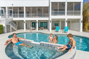 A residential pool area with a two-story house, a covered deck, and a staircase leading to the upper level. - Bradenton Beachfront Pool Game Room (Bradenton)