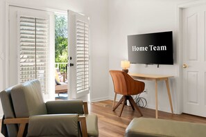 Ein Zimmer mit Fernseher an der Wand, einem Schreibtisch und zwei Stühlen.