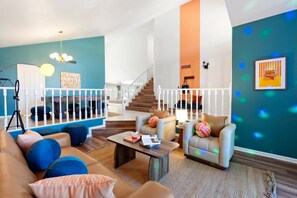 Un salon moderne avec un escalier, un ensemble de canapés et une table basse.