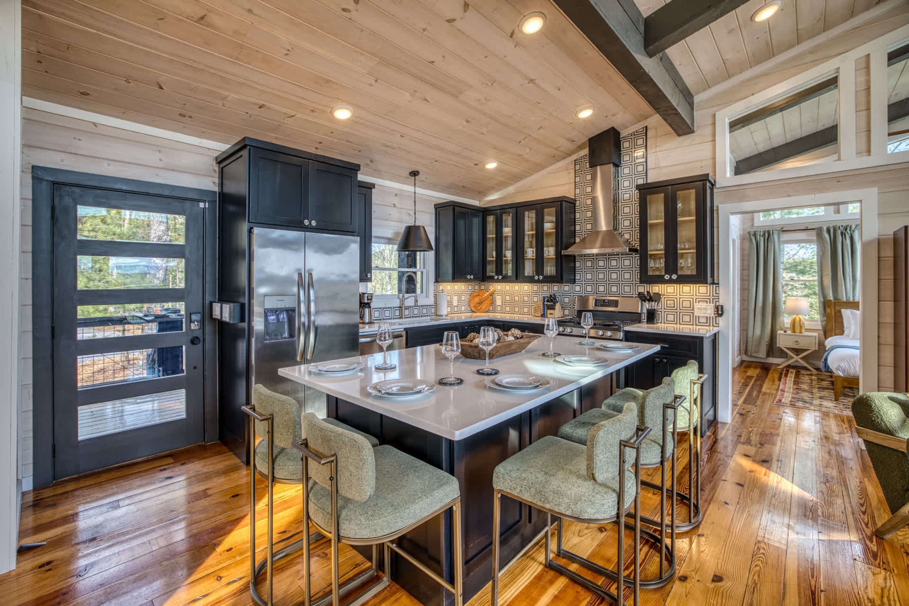 A modern kitchen with a central island, bar stools, and a large refrigerator.