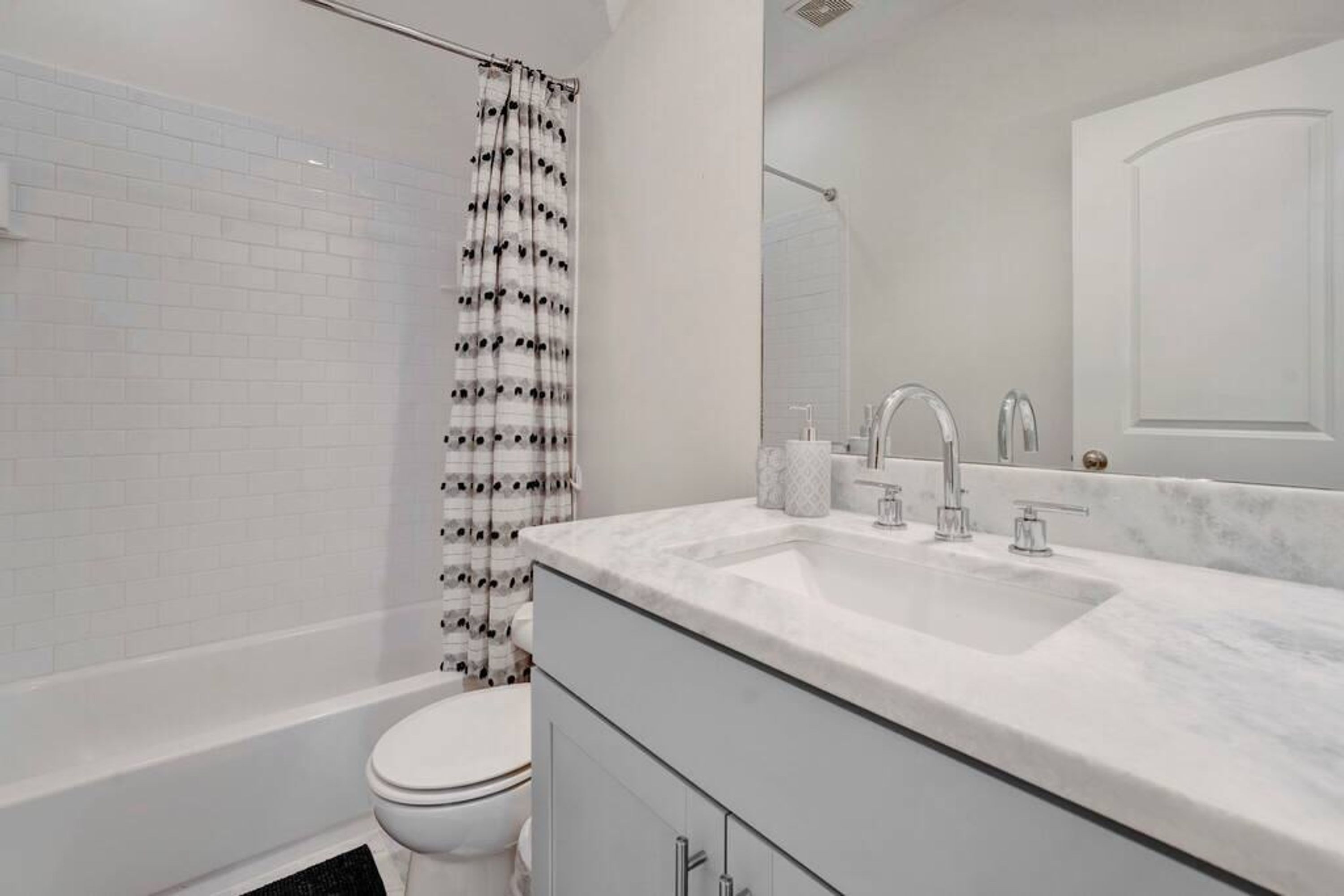 Een moderne badkamer met een witte badkuip, toilet en douche.