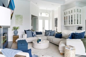 A modern living room with a sectional sofa, a round coffee table, and a white fireplace. - Marco Island Escape Pool Game Room (Marco Island)