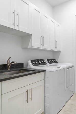 A laundry room with white cabinets, a washing machine, and a sink with a faucet. - Marco Island Escape Pool Game Room (Marco Island)