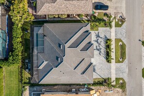 A multi-level building with a geometric roof design, surrounded by a landscaped area with palm trees. - Marco Island Escape Pool Game Room (Marco Island)