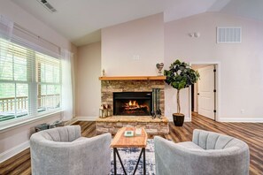 A living room with a stone fireplace, two grey armchairs, a coffee table, and a potted plant. - Secluded Escape Fire Pit Gazebo Dog Welcome (Blue Ridge)