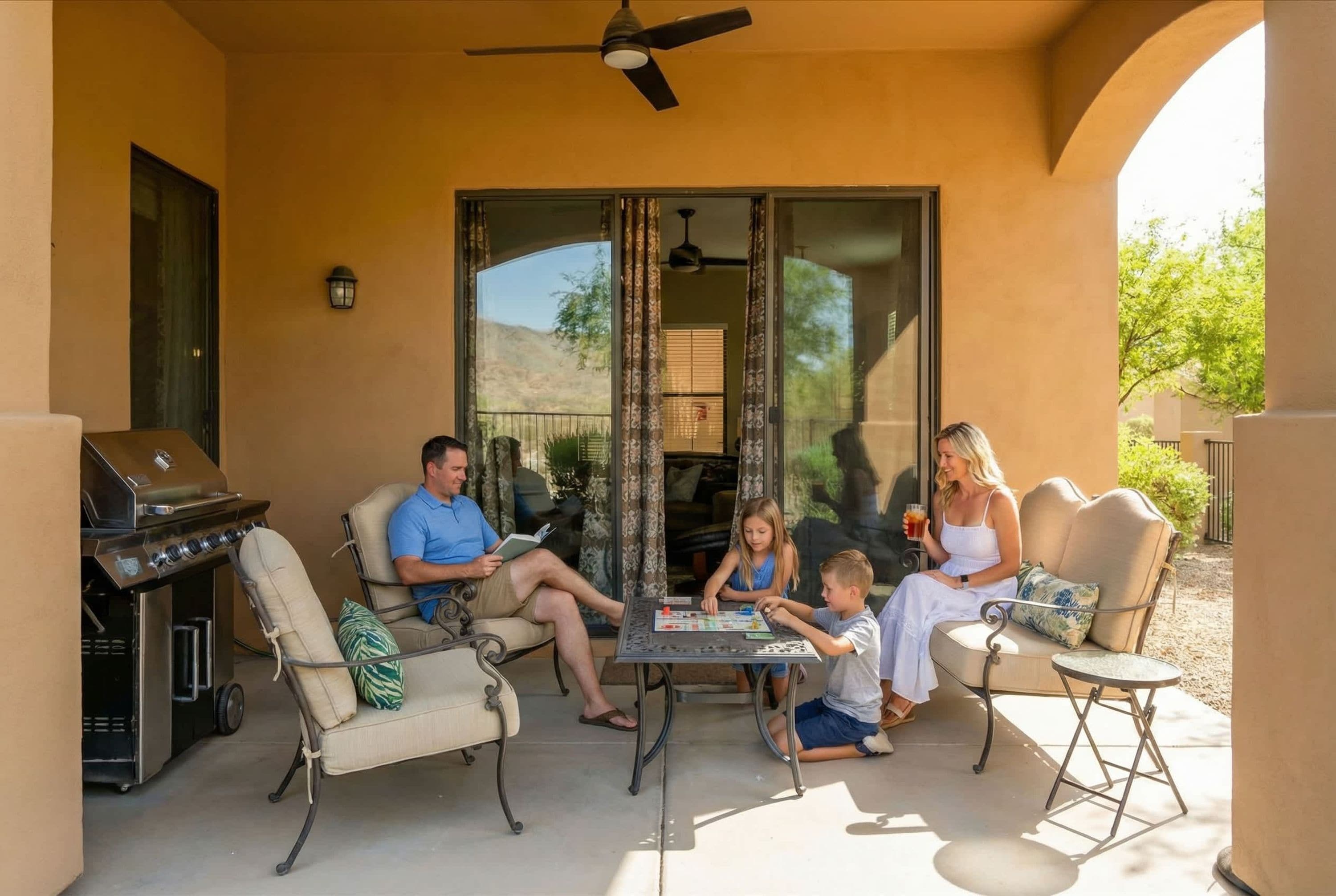 A family of four seated on patio furniture with a grill and a ceiling fan in the background.