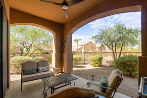 A covered patio with a ceiling fan, a sofa with cushions, a metal table, and chairs. - Shared Poolside Fun Hot Tub Gym More (Phoenix)
