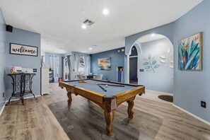 A pool table in a room with a 'welcome' sign, a table with books, and a painting on the wall. - Heated Pool Game Room Outdoor Fun Sleeps 6 (Tampa)