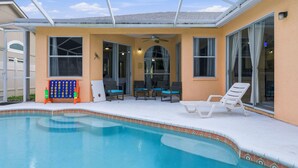 A swimming pool with a covered patio area, including lounge chairs and a ceiling fan. - Heated Pool Game Room Outdoor Fun Sleeps 6 (Tampa)