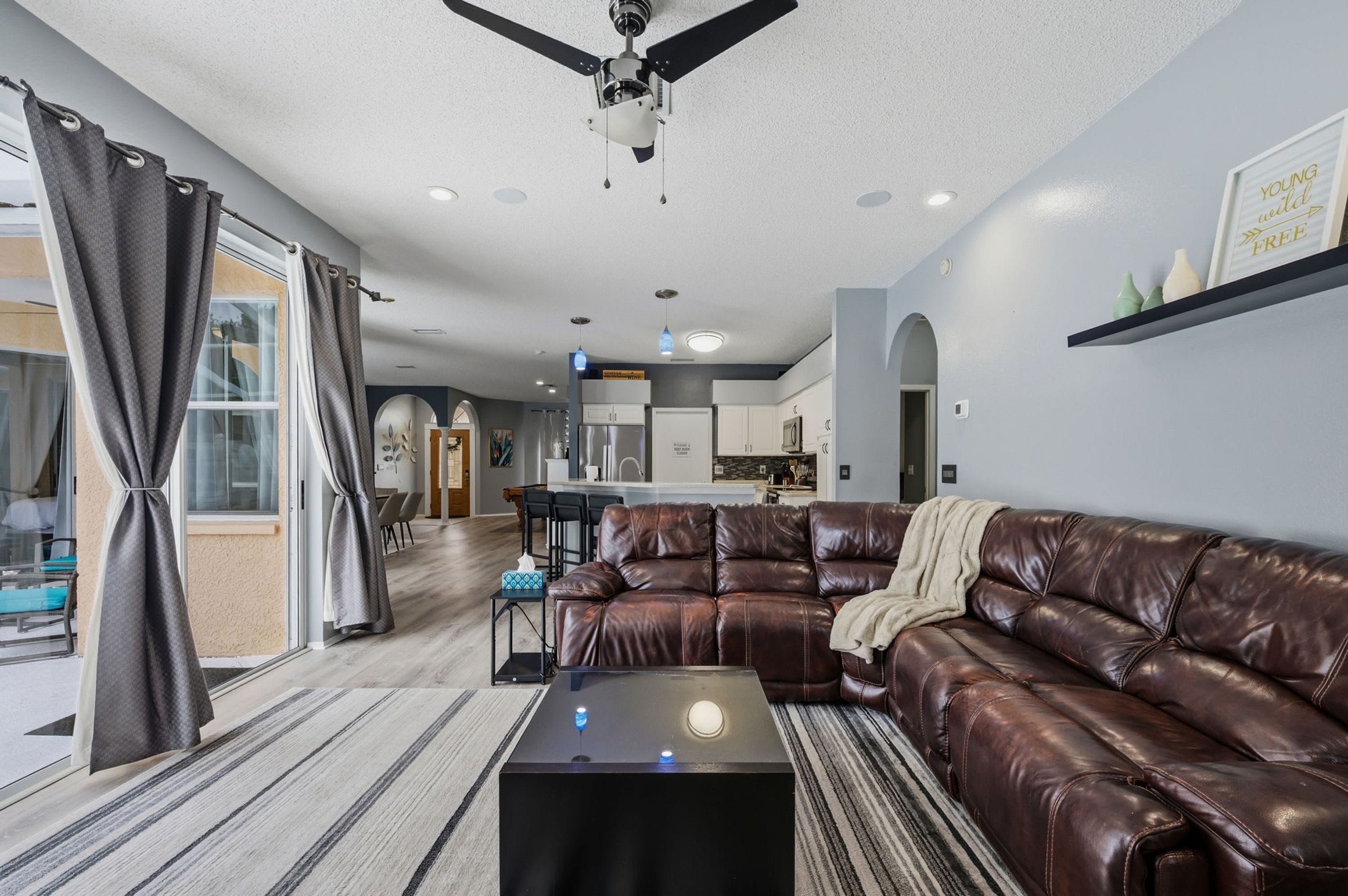 A modern living room with a leather sofa, a coffee table, and a ceiling fan.