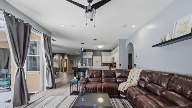 A modern living room with a leather sofa, a coffee table, and a ceiling fan. - Heated Pool Game Room Outdoor Fun Sleeps 6 (Tampa)