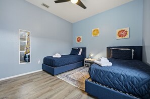 Ein Schlafzimmer mit zwei Betten, einem Deckenventilator und einem Spiegel.