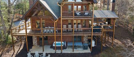 A multi-level log cabin with outdoor seating, a fire pit, and a deck.